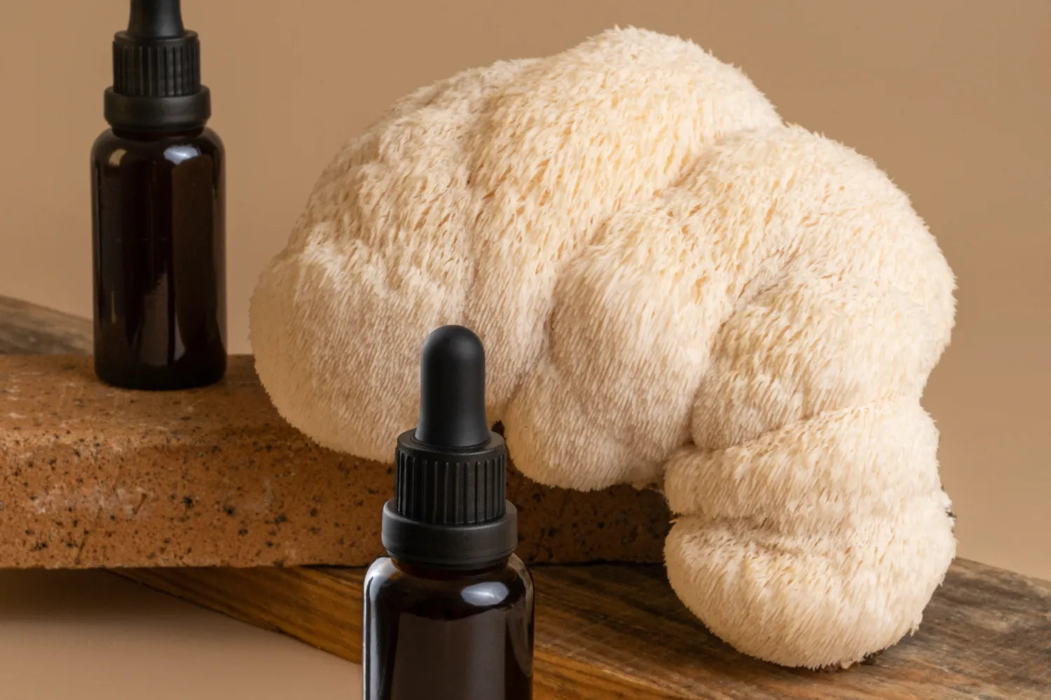 Lion’s mane mushroom beside amber glass dropper bottles on a wooden board