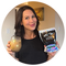 Woman smiling holding a glass of everydaydose coffee in one hand, a bag of everydaydose powder in the other 
