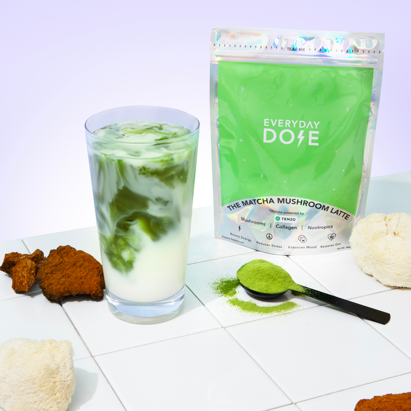 Mushroom Matcha powder package with iced latte drink, green powder on spoon, and ingredients on white tile surface