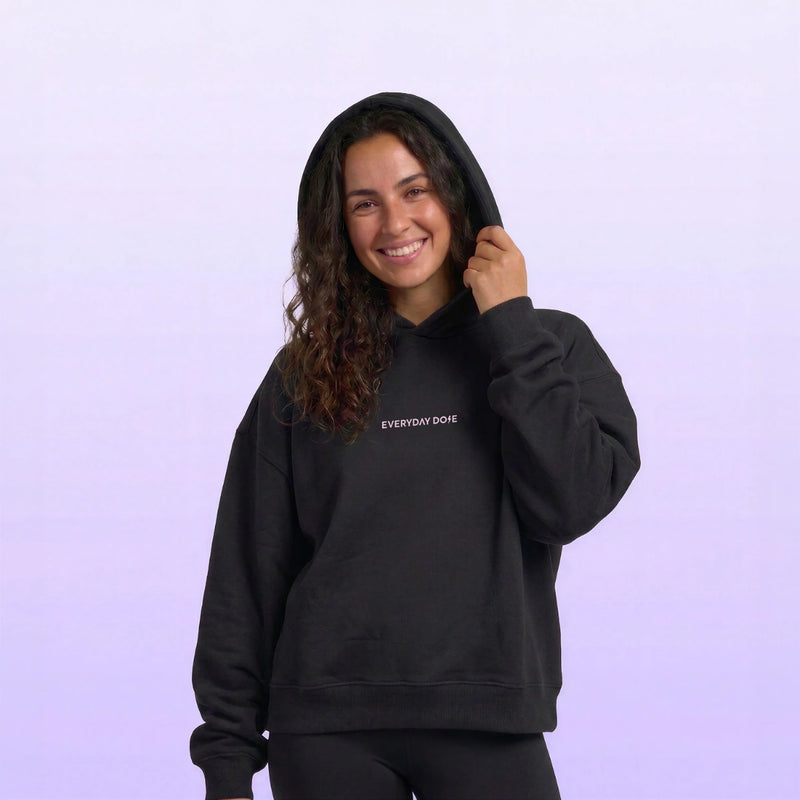 Model wearing a black hooded sweatshirt against a soft purple backgroundcuntegn