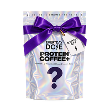 Holographic pouch labeled Everyday Dose Protein Coffee with a large question mark purple bow and Mystery Gift tag