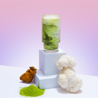 Mushroom Matcha+ starter kit with frothy green drink, powdered matcha, white mushrooms and chaga on display pedestals