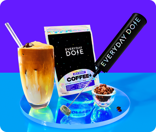Front view of Everyday Dose mild roast coffee bag with iced latte, frother, and bowl of coffee beans on reflective blue surface